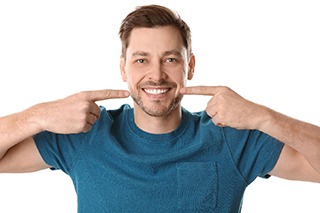 A man in blue shirt pointing to smile after cosmetic bonding treatment