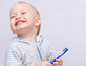 Toddler with toothbrush smiling during pediatric dentistry