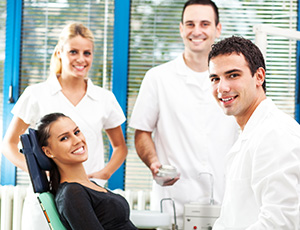 Smiling woman in dental chair with team members