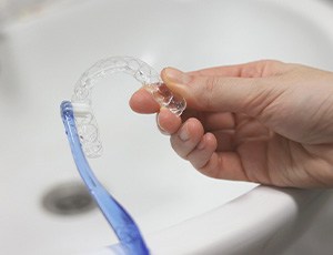 Patient using toothbrush to clean aligner