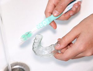 Person brushes sportsguard with toothbrush