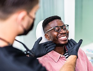 Dentist with black gloves looking at patient’s smile