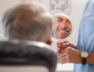 Man smiling at reflection in handheld mirror