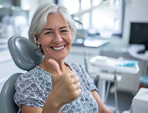Older woman giving thumbs up in treatment chair