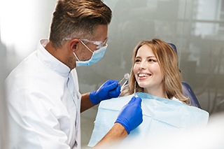 A young female smiling as a dentist prepares to check her smile