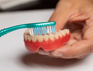 Man brushing dentures with a toothbrush