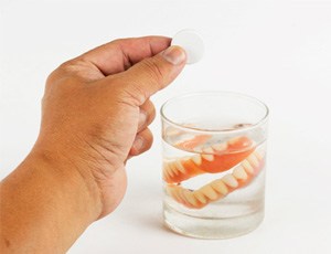 Dentures soaking in a glass of water