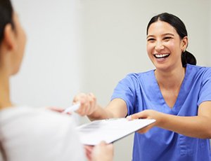 a front desk member handing a form to a patient