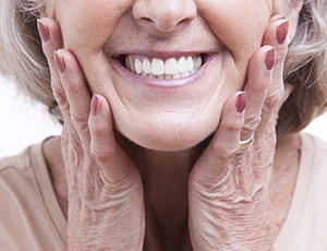 close-up of an elderly woman smiling and holding the sides of her face