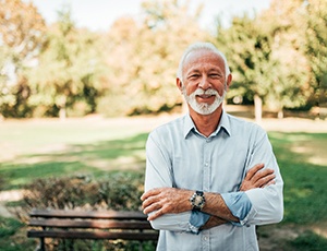 Senior man outside smiling with arms folded