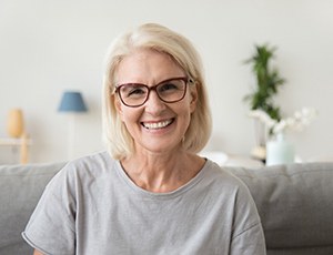 Woman with glasses sitting on couch smiling