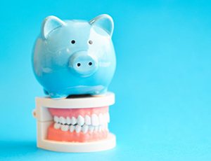 blue piggy bank sitting on top of a set of full dentures 