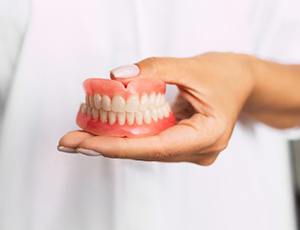 dentist holding a set of full dentures 