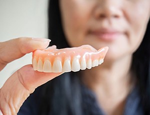 A woman holding a denture in her hand
