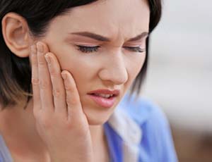 Pained woman who needs to visit her Plano emergency dentist