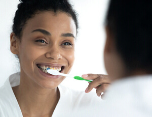 Woman brushes teeth in Plano