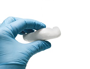 Dentist holding mouthguard to protect dental implants in Plano