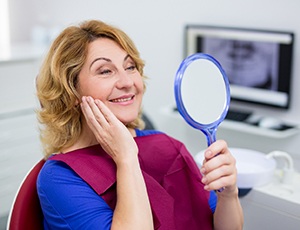 woman admiring her new implant dentures in Plano, TX 