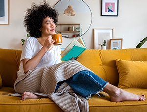 person relaxing while sipping on a drink and reading