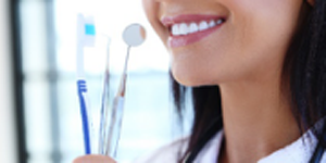 Woman smiling holding dental tools