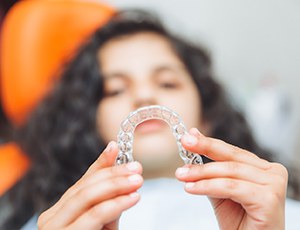Plano teen holding Invisalign Teen aligner 