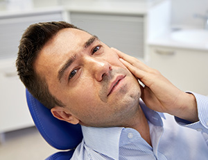 Man in pain holding cheek before root canal therapy