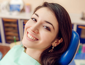 Smiling woman in dental chair after tooth extraction
