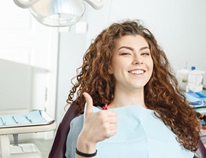 woman giving thumbs up in dental chair 