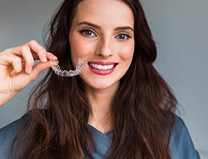 Woman holding SureSmile aligner in Plano