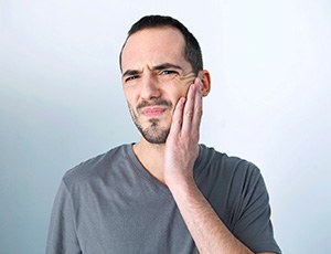Man with TMJ disorder in Plano, TX rubbing jaw looking concerned