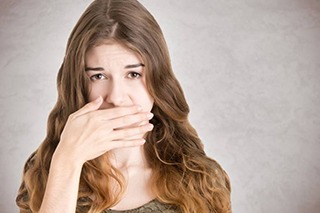 woman in need of tooth extraction covering her mouth