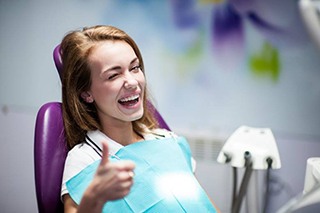 woman smiling and giving a thumbs up after tooth extraction