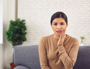 Woman with tooth pain on couch