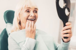 an older woman looking at her smile in the mirror