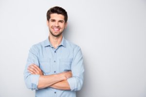 a young man smiling with his arms crossed