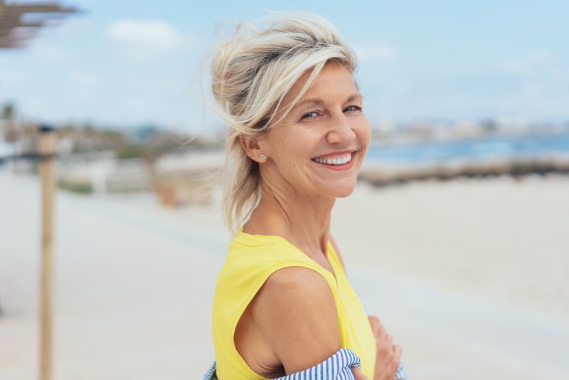 Woman with dental implants smiling by the lake