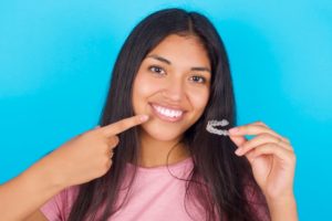 happy patient holding a clear aligner