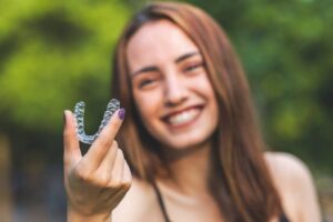 Woman smiling while holding her Invisalign