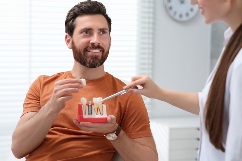 man holding dental implant mold and listening to dentist 