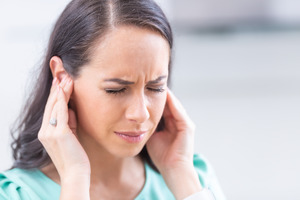 Woman rubbing her ears and looking uncomfortable