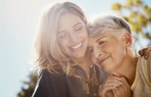 Woman smiling and embracing her older mother.